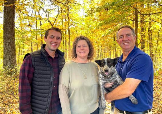 Three people standing and one person holding a dog